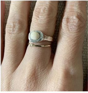 Close-up of stacked S925 silver rings with oval opal gemstone on a hand over fabric