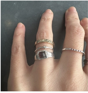 Detail of stacked S925 silver rings with red gemstone and diamonds on a hand