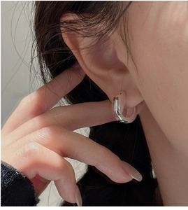 Close-up of polished S925 sterling silver U-shaped hoop earring worn on model's ear