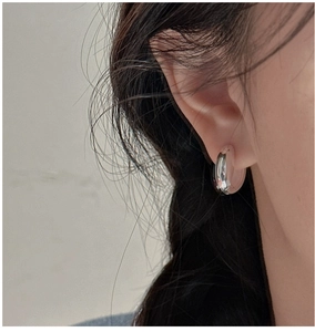 Close-up of a model wearing the polished silver S925 sterling silver U-shaped huggie earring