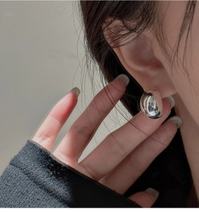 Close-up of polished S925 sterling silver bean earrings worn on model's ear