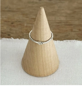 Detail of thin S925 sterling silver ring with hammered texture on a wooden stand