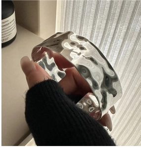 Detail of wide S925 silver cuff bracelet with hammered texture and mirror finish