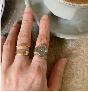 Gros plan d'une bague sceau en argent vintage et d'anneaux dorés portés sur la main du modèle