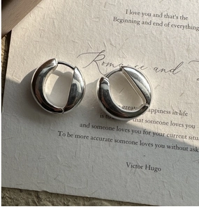 Macro detail of polished S925 sterling silver U-shaped hoop earrings on vintage paper