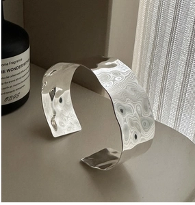 Macro detail of wide S925 silver cuff bracelet featuring unique hammered water ripple texture