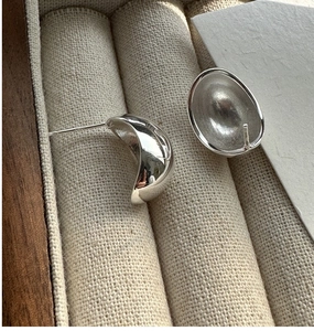 Macro view of polished S925 sterling silver minimalist earrings in a wooden jewelry box