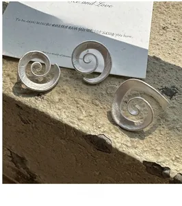 Artistic S925 sterling silver spiral earrings with a brushed matte texture on stone surface