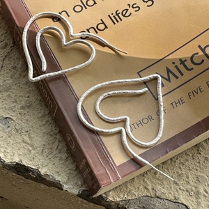 Matte S925 sterling silver heart earrings with layered line design on vintage book