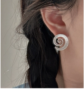 Close-up of a vintage S925 sterling silver spiral earring worn by a model in soft light