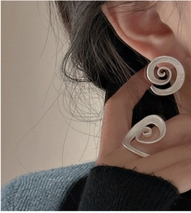 Close-up of matte silver spiral earring and ring set with minimalist abstract design
