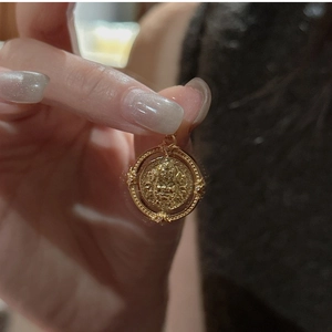 Gros plan d'un pendentif médaille doré avec relief de déesse mythologique style vintage