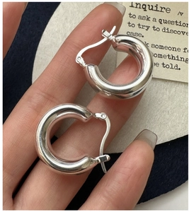 Close-up of chunky silver S925 sterling silver hoop earrings on a textured background