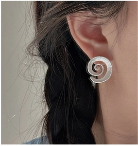 Macro detail of silver S925 spiral earrings showing delicate hammered texture and curves