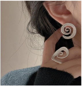 Detailed view of matte S925 sterling silver spiral earrings and ring on a model