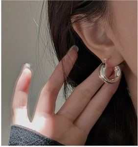 Close-up of minimalist silver hoop earrings on a model showing the polished mirror finish