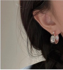 Close-up of polished S925 sterling silver chunky hoop earrings worn by a model