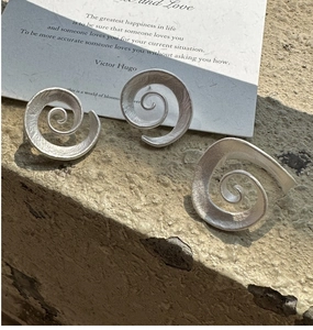 Detailed macro view of S925 silver irregular vortex earrings with a matte brushed texture