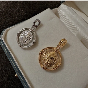 Détail de pendentifs pièces vintage avec relief de portrait en finitions or et argent