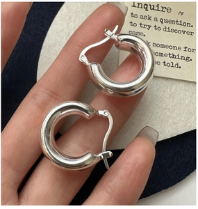 Close-up of polished S925 sterling silver hollow hoop earrings held by hand
