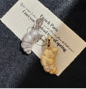 Detailed view of croissant-shaped pendants with brushed finish and zircon accents
