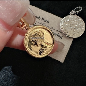 Macro detail of retro coin pendant featuring female portrait relief and zircon inlay