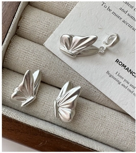 Macro detail of S925 sterling silver butterfly earrings and pendant with matte finish