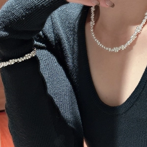 Polished S925 sterling silver beaded necklace and bracelet set on a black knit background