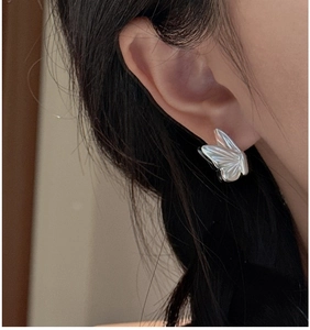 Detailed view of 925 sterling silver butterfly earrings worn on a model's ear