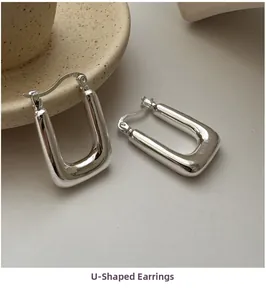 Close-up of polished S925 sterling silver U-shaped earrings with minimalist design
