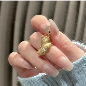 Macro view of a gold croissant pendant with matte finish and fine diamond-encrusted rows