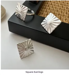 Macro detail of square silver earrings with radiating textured matte finish