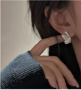 Detailed close-up of a matte S925 sterling silver butterfly earring worn by a model