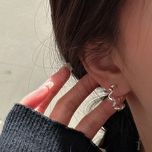 Eleganti orecchini in argento 925 con design a onde minimalista indossati sul modello