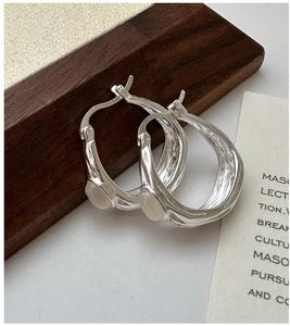 Close-up of 925 silver ear cuffs with hammered texture and white moonstone inlay