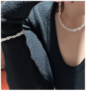 Detailed view of silver beaded weave bracelet on wrist against black sweater background