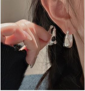 Detail of 925 sterling silver hoop earrings with black oval agate in minimalist style