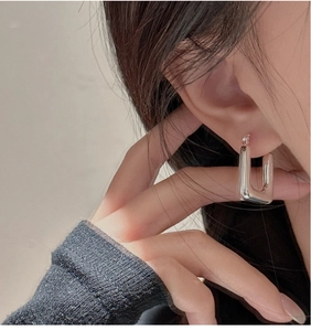 Close-up of minimalist S925 sterling silver rectangular hoop earrings worn on ear