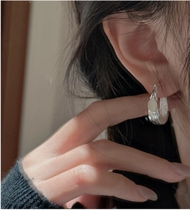 Close-up of 925 sterling silver earrings with wavy texture and white oval stone