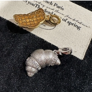 Macro shot of silver croissant and waffle charms with brushed finish and crystals