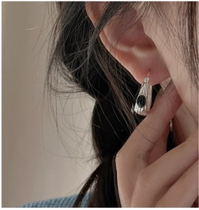 Close-up of 925 silver ear buckle with black oval agate and hand-crafted texture
