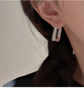 Detailed view of polished S925 sterling silver rectangular hoop earring on model