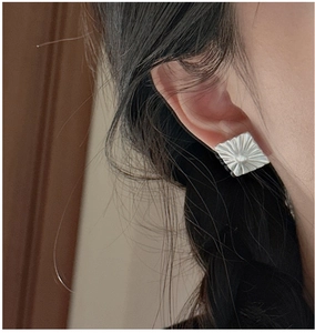 Macro view of S925 sterling silver square earrings with matte radial texture on model