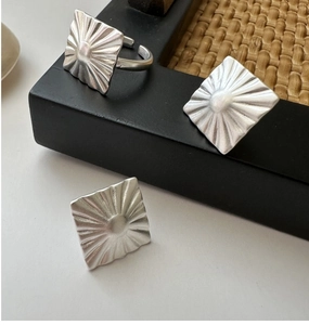 Macro detail of square matte silver rings featuring sunburst texture and open band design