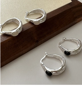 Detail of 925 silver hoop earrings with irregular texture and black agate stone
