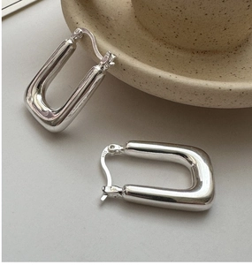 Macro view of S925 sterling silver stamp on polished U-shaped earrings with minimalist design