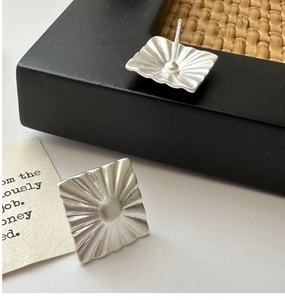 Macro shot of S925 sterling silver stamp on minimalist matte square stud earrings