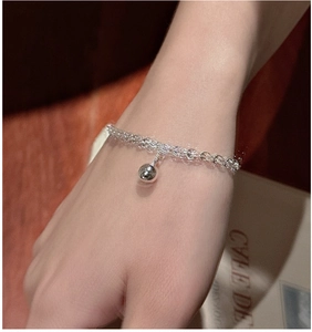 Détail d'un bracelet multi-chaînes en argent avec perle polie porté sur le poignet