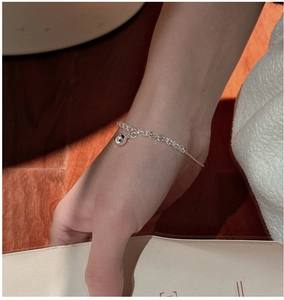 Gros plan d'un bracelet minimaliste en argent 925 avec breloque boule au poignet