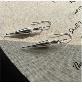 Close-up of matte S925 sterling silver drop earrings on rustic canvas background